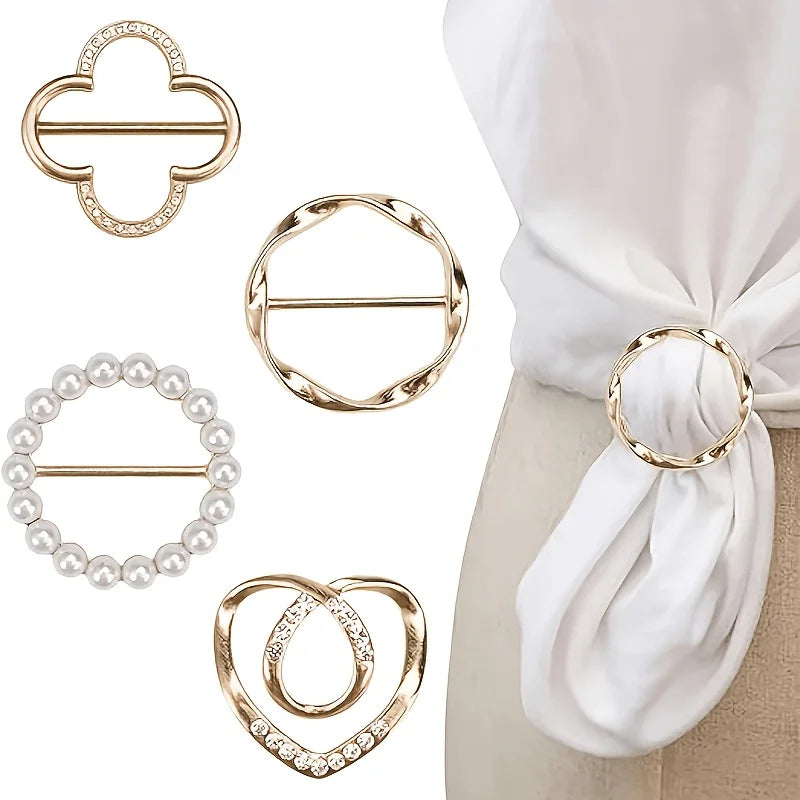 A set of elegant gold-toned metal clips and a pearl bracelet displayed against a white fabric background.