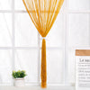 A bright golden thread curtain tie-back hanging from a window, with a small potted plant nearby.