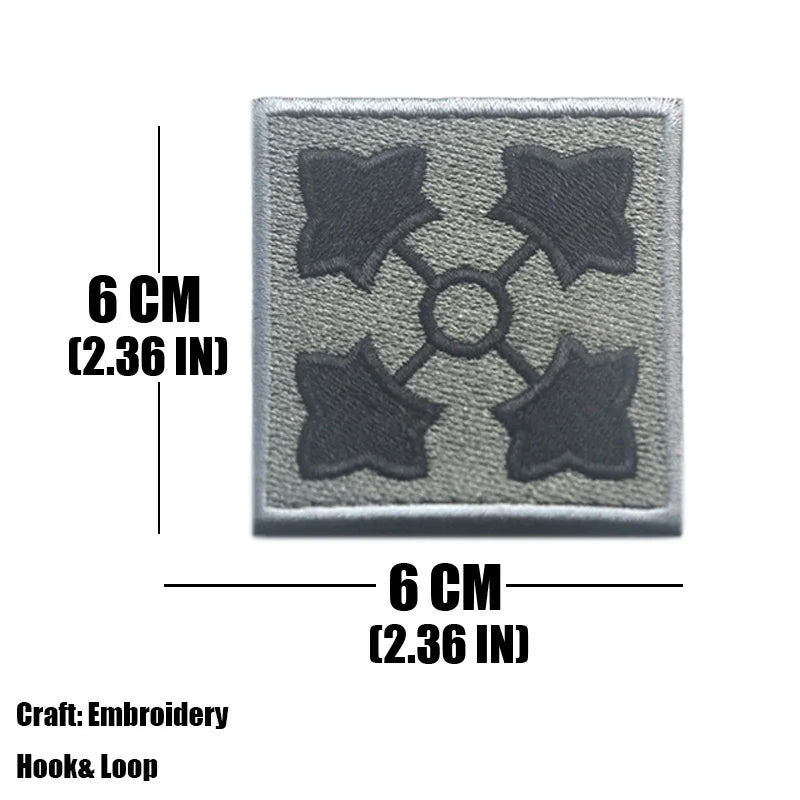 A square gray embroidered tactical patch featuring four dark star shapes arranged in a cross pattern.