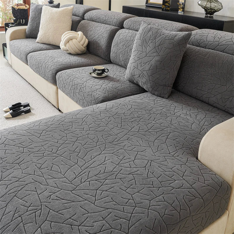 A gray patterned jacquard sofa cover featuring a textured fabric and light beige trim.