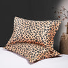 Two leopard print silk satin pillowcases displayed on a white surface against a dark background.