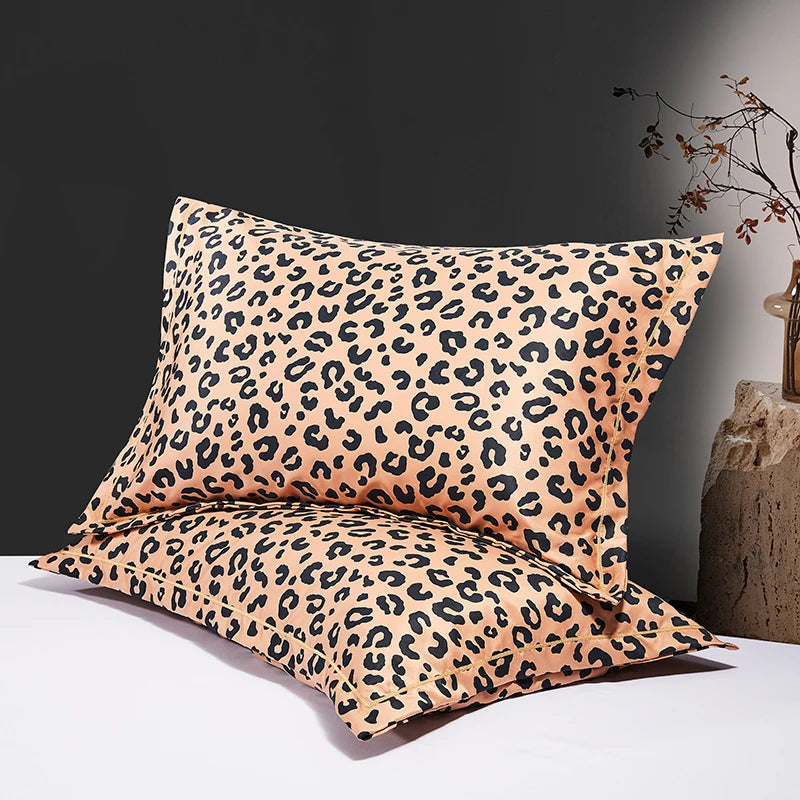 Two leopard print silk satin pillowcases displayed on a white surface against a dark background.