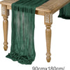 A dark green semi-sheer gauze table runner draped over a wooden table.