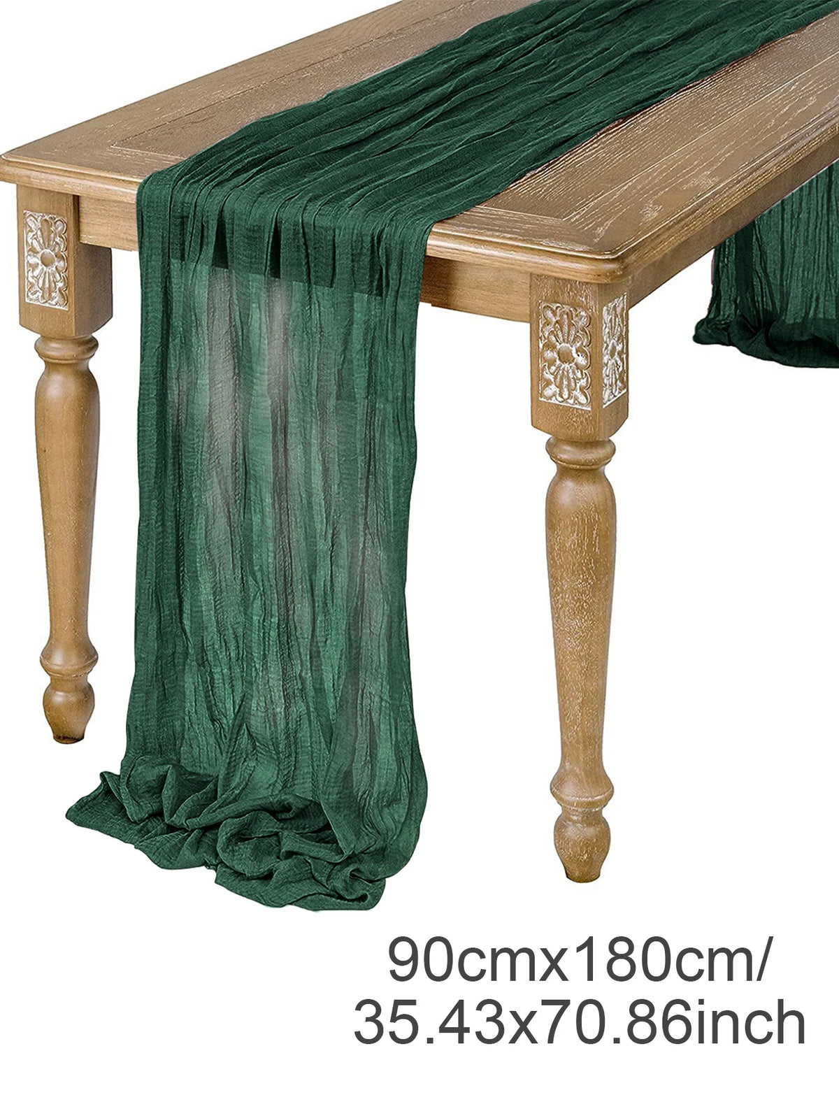 A dark green semi-sheer gauze table runner draped over a wooden table.