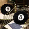 A black memory foam ball pillow cushion resting on a gold wire chair.