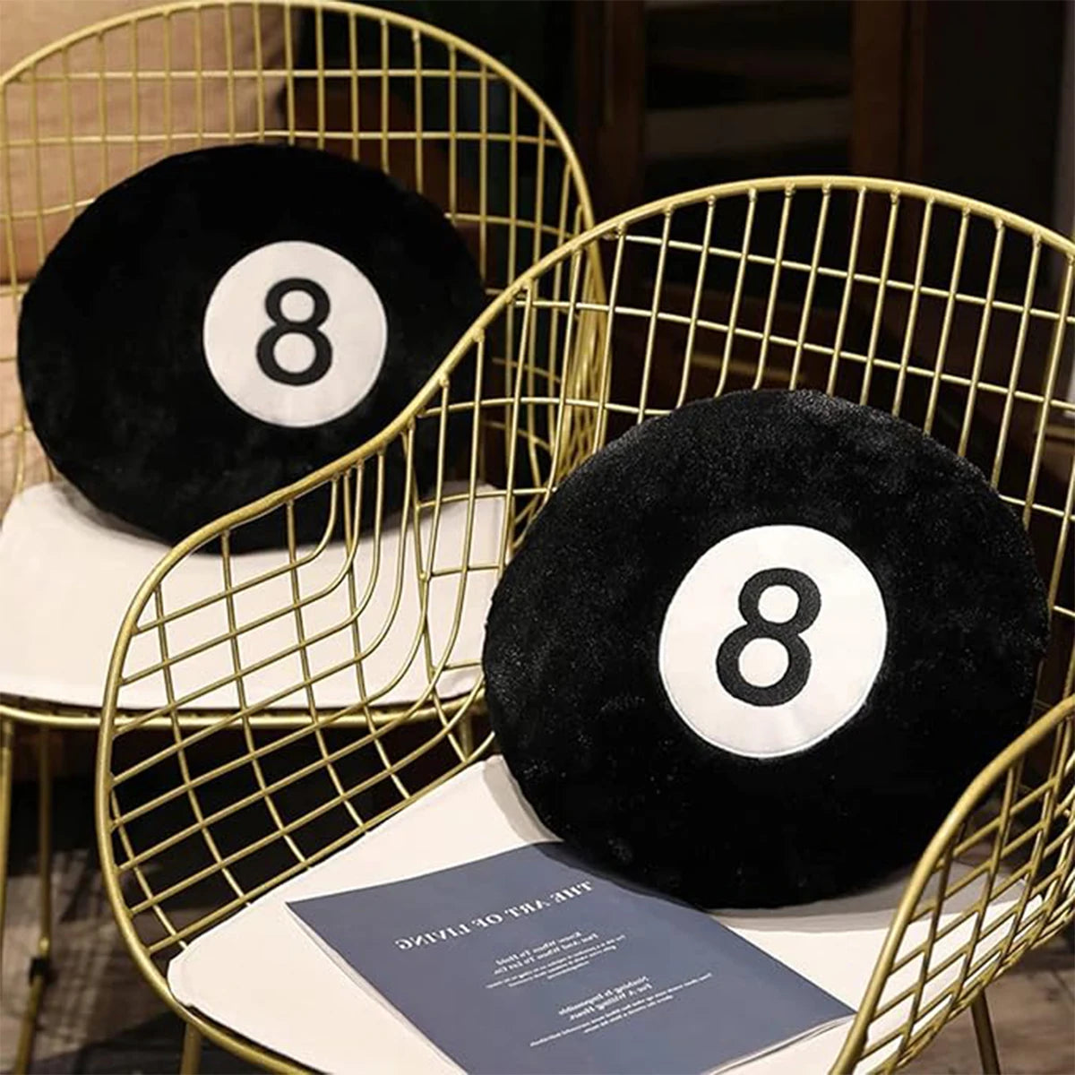 A black memory foam ball pillow cushion resting on a gold wire chair.