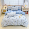 A light blue cotton duvet cover and pillow set displayed on a bed with white wooden furniture and a window in a bright room.