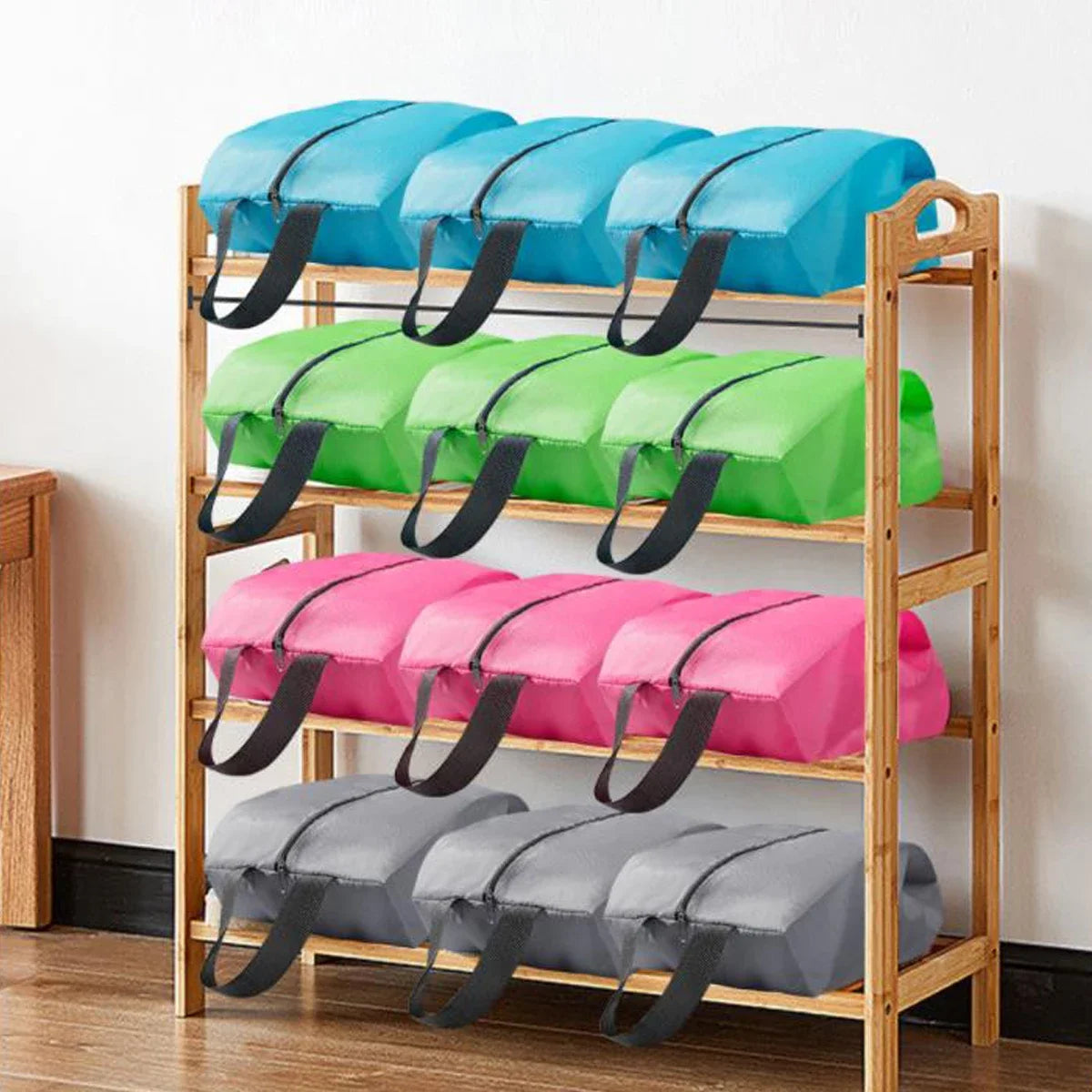 A wooden shelf displaying several colorful foldable shoe and travel organizer bags in blue, green, pink, and gray.