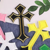 A set of multi-color cross embroidery patches featuring black, gold, pink, and yellow designs on a dark blue fabric.
