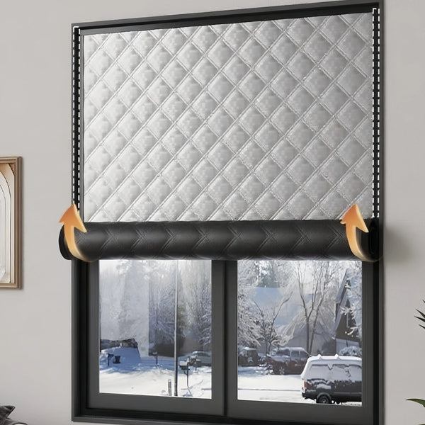 A close-up of a window with a quilted silver thermal film applied, showing an exterior winter scene.