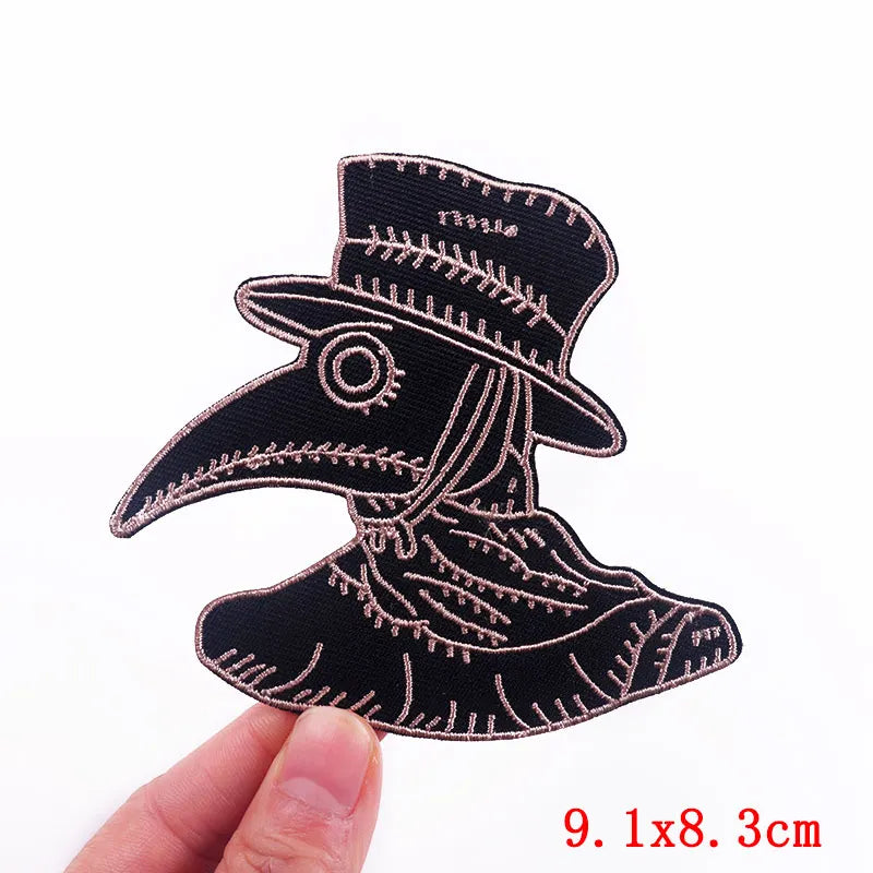 Black embroidered skull iron-on patch with a detailed design on a finger