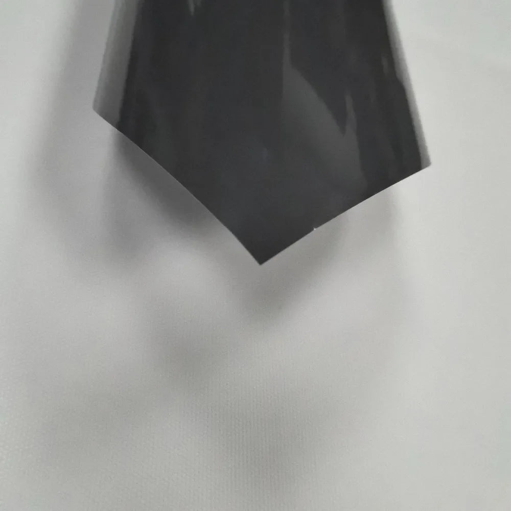 A black heat transfer vinyl sheet is angled against a light gray background.