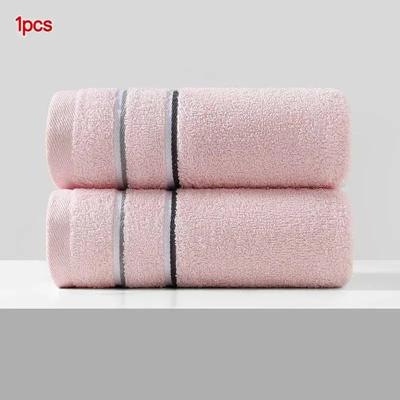Two pink ultra-absorbent pure cotton face towels rolled up and displayed on a white surface.