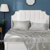 A white upholstered headboard with a satin gray pillowcase and sheet on a bed.