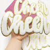 Hand holding a gold glitter embroidered patch spelling the word Cheer