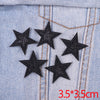 Five black glitter star patches are embroidered onto a light blue denim fabric.