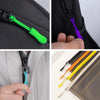 Close-up view of replacement zipper pulls in green, purple, and blue colors on a black fabric bag.