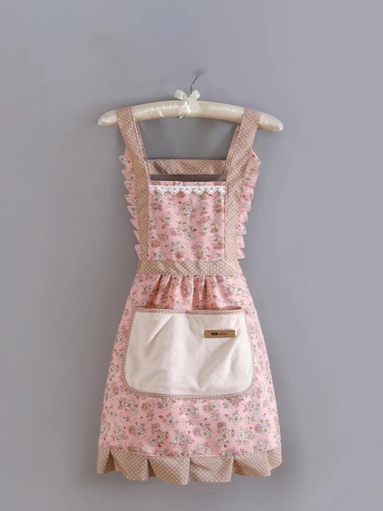 A pink floral pattern kitchen apron with a bib and adjustable strap hanging on a wooden hanger.