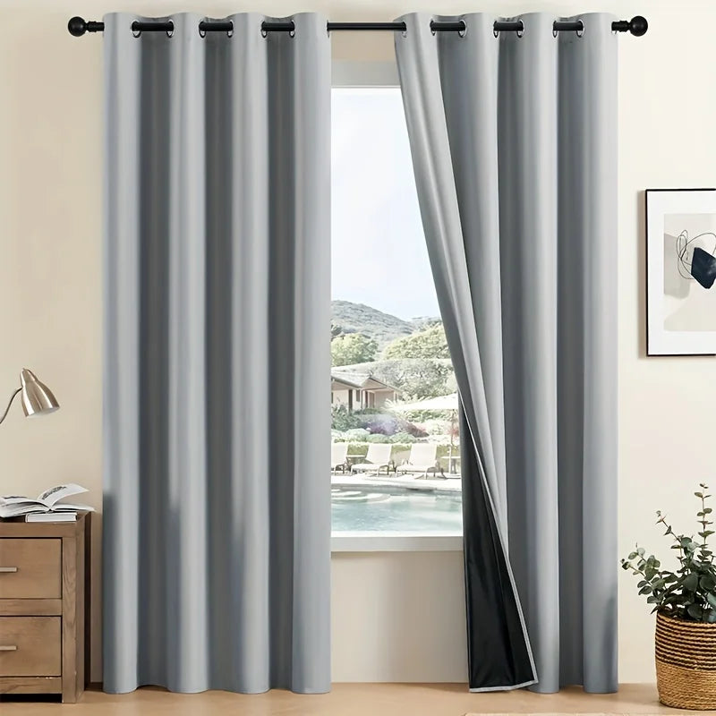A set of two modern gray blackout grommet curtains hanging in a window frame.
