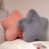 Two star-shaped decorative throw pillows in peach and gray resting on a white surface.