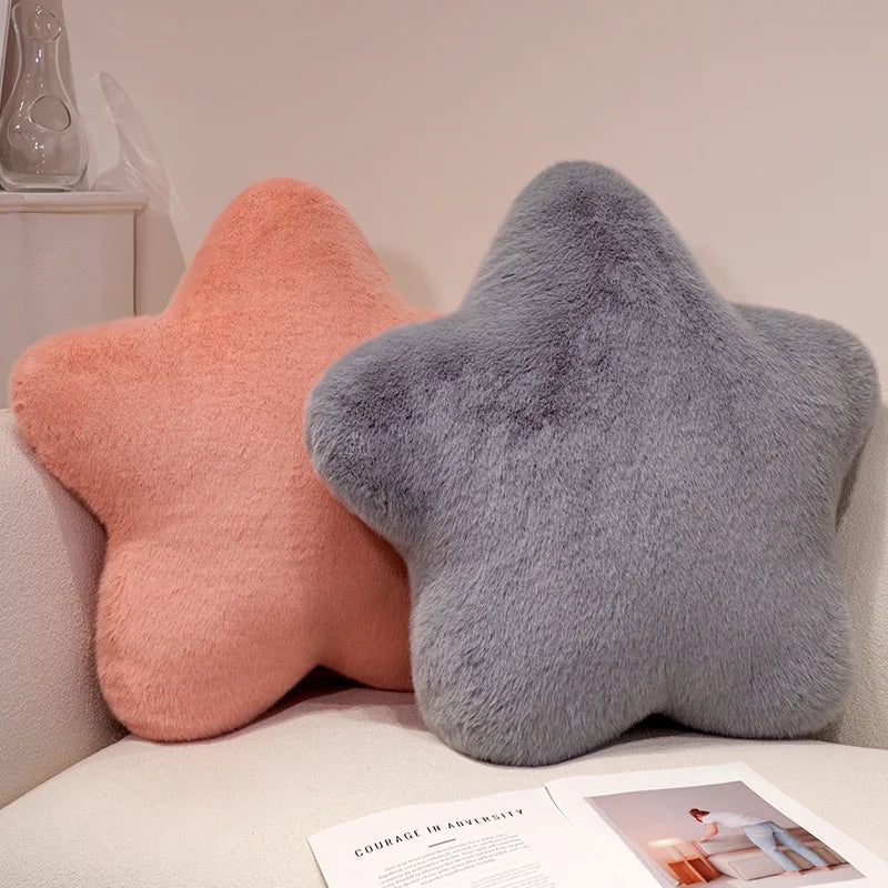 Two star-shaped decorative throw pillows in peach and gray resting on a white surface.