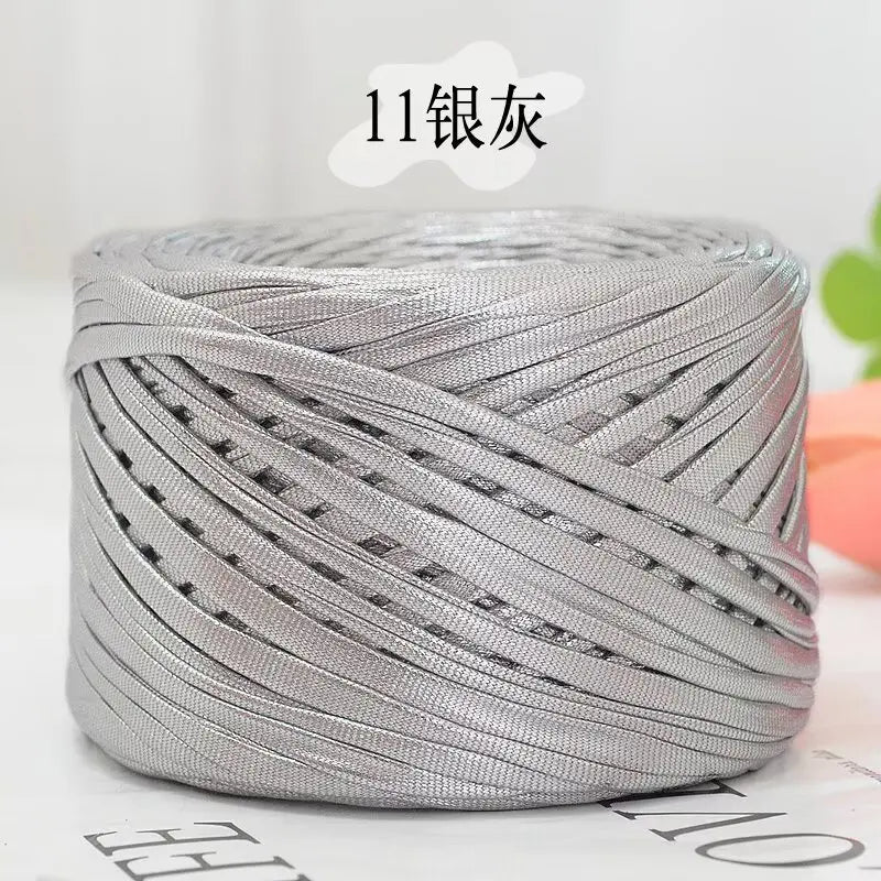 A spool of silver metallic cake yarn for crafting, tightly wound and cylindrical.