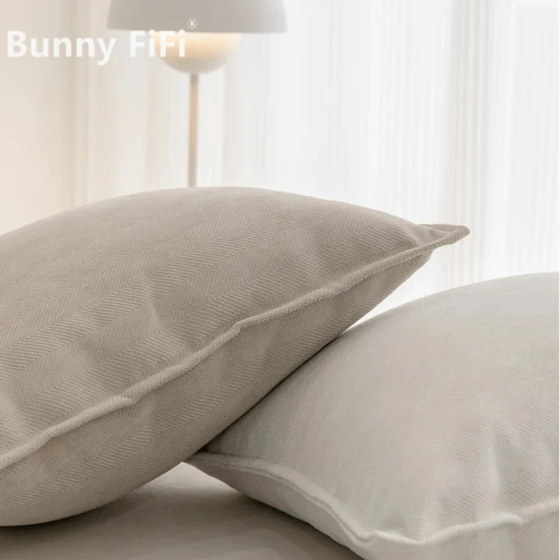 A close-up of two solid beige chenille throw pillow covers on a white surface.