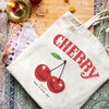 A white canvas shopping bag featuring a red cherry design and the word CHERRY printed in red ink.