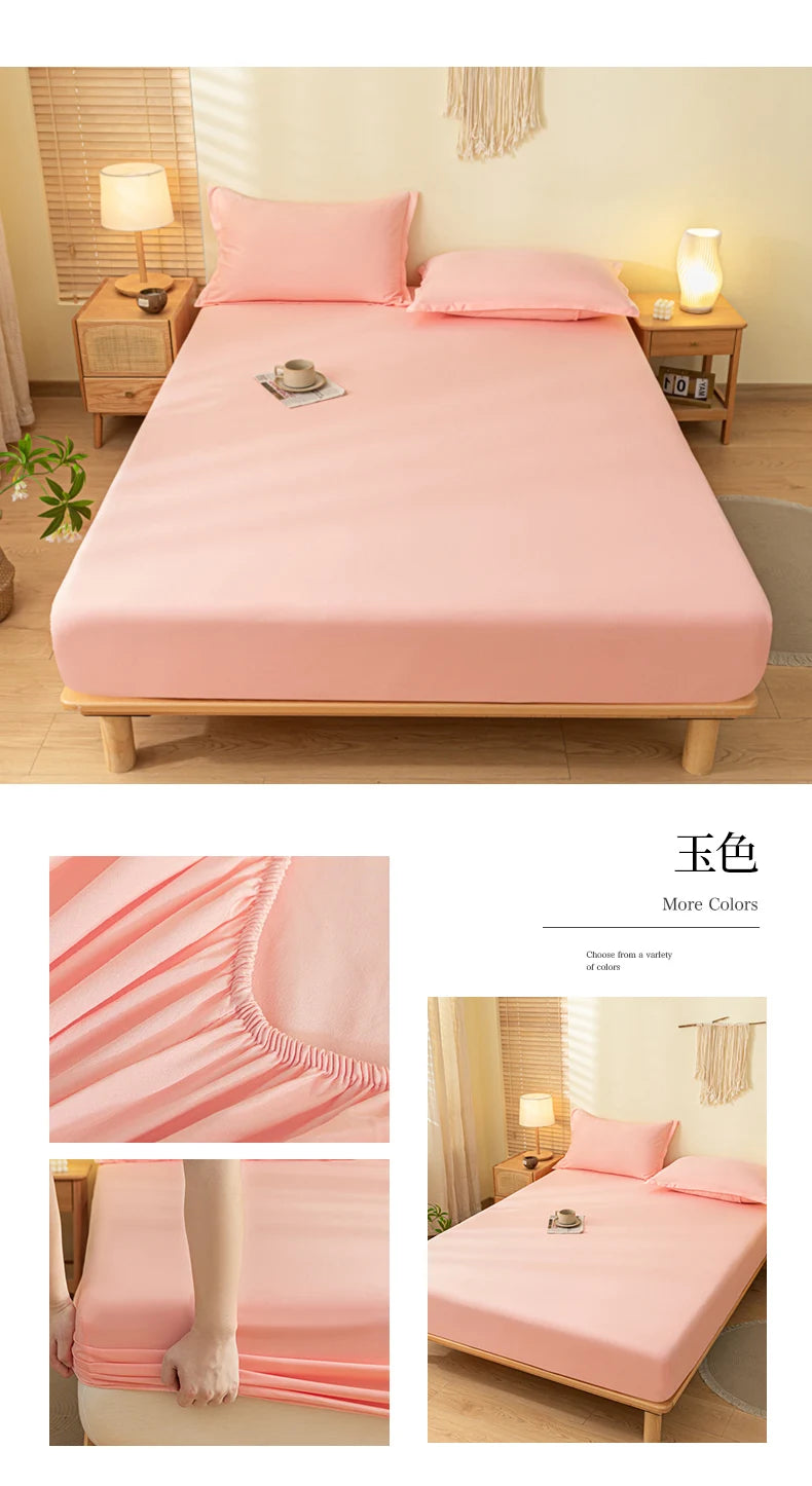 A pink fitted bed sheet set is displayed on a wooden bed frame with pillows and bedside lamps.