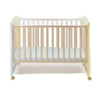 A wooden crib with a sheer mosquito net draped over the top.