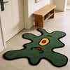 A green area rug shaped like a playful one-eye monster with yellow eyes and red mouth on a light floor.