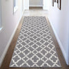 A rectangular gray and white geometric patterned area rug placed in a hallway with light wood flooring.