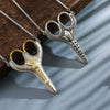Silver and gold vintage stainless steel sewing scissors hanging on a chain