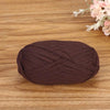 A ball of dark brown flat thread yarn lying on a wooden surface.