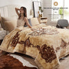 A beige weighted blanket is draped over a bed, with a woman sitting beside it in a bright bedroom.