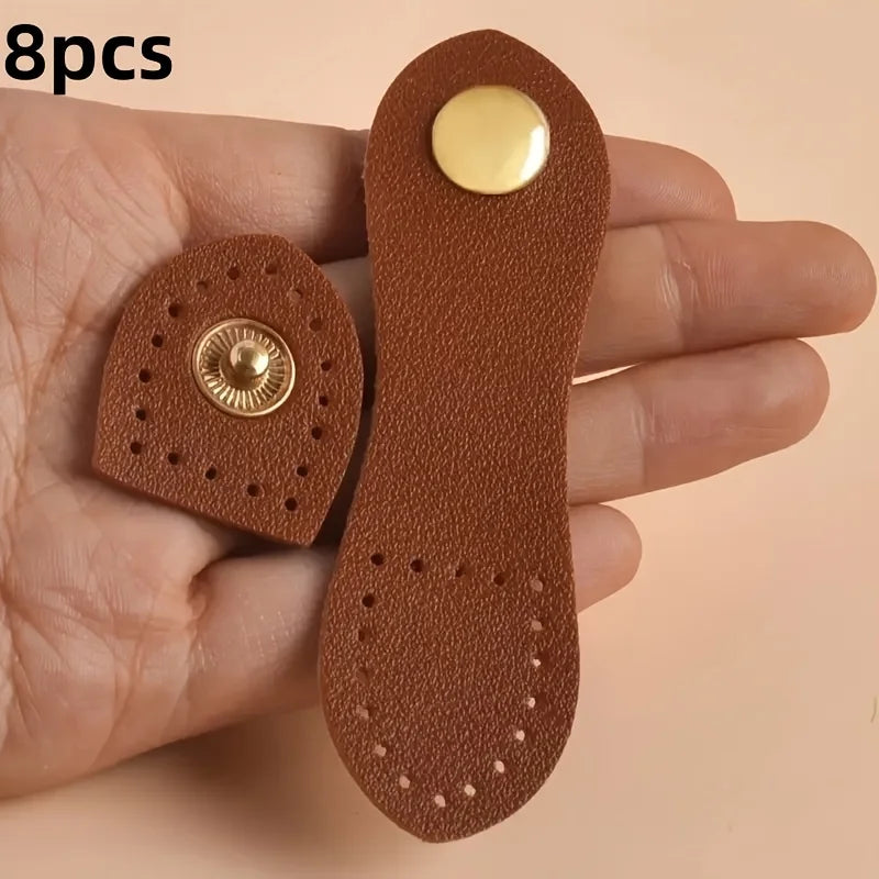 A hand holds eight brown leather bag buttons, some with gold accents, against a light background.