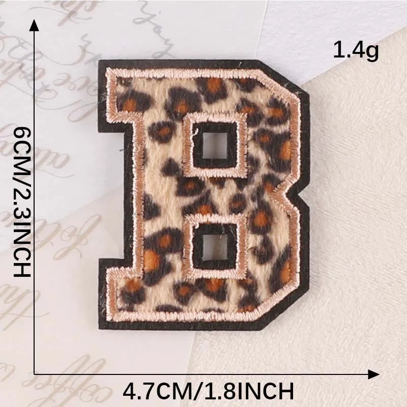 A black iron-on patch shaped like the letter B with a leopard print design.
