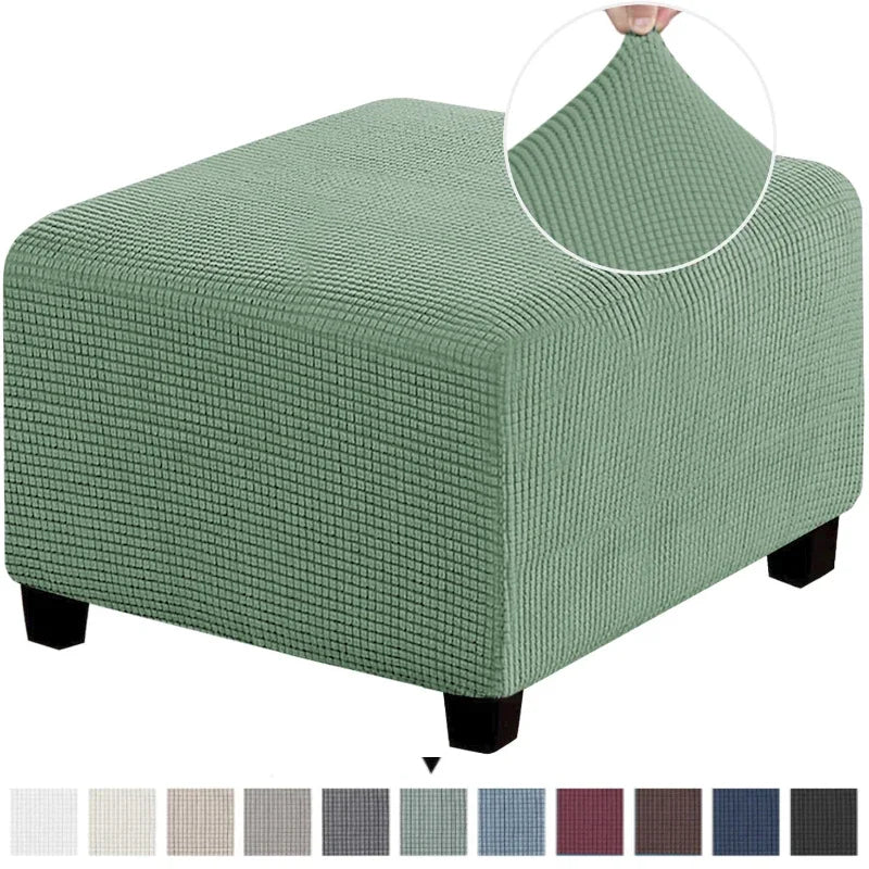 A square jacquard footrest ottoman slipcover in a muted sage green fabric.