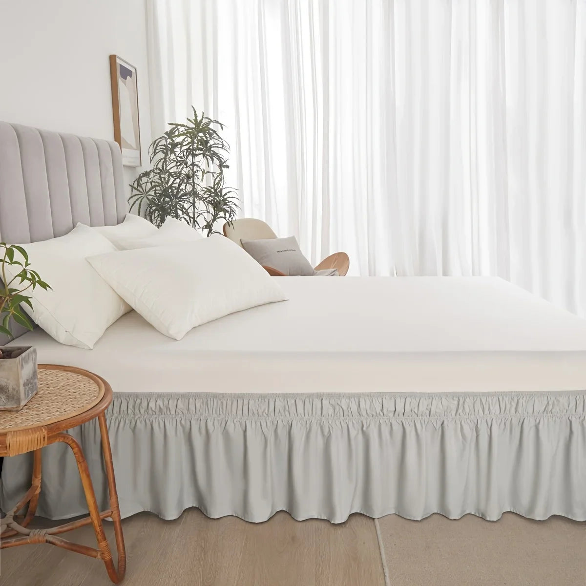 A bed featuring a light gray adjustable elastic bed skirt with a ruffled trim and white bedding.