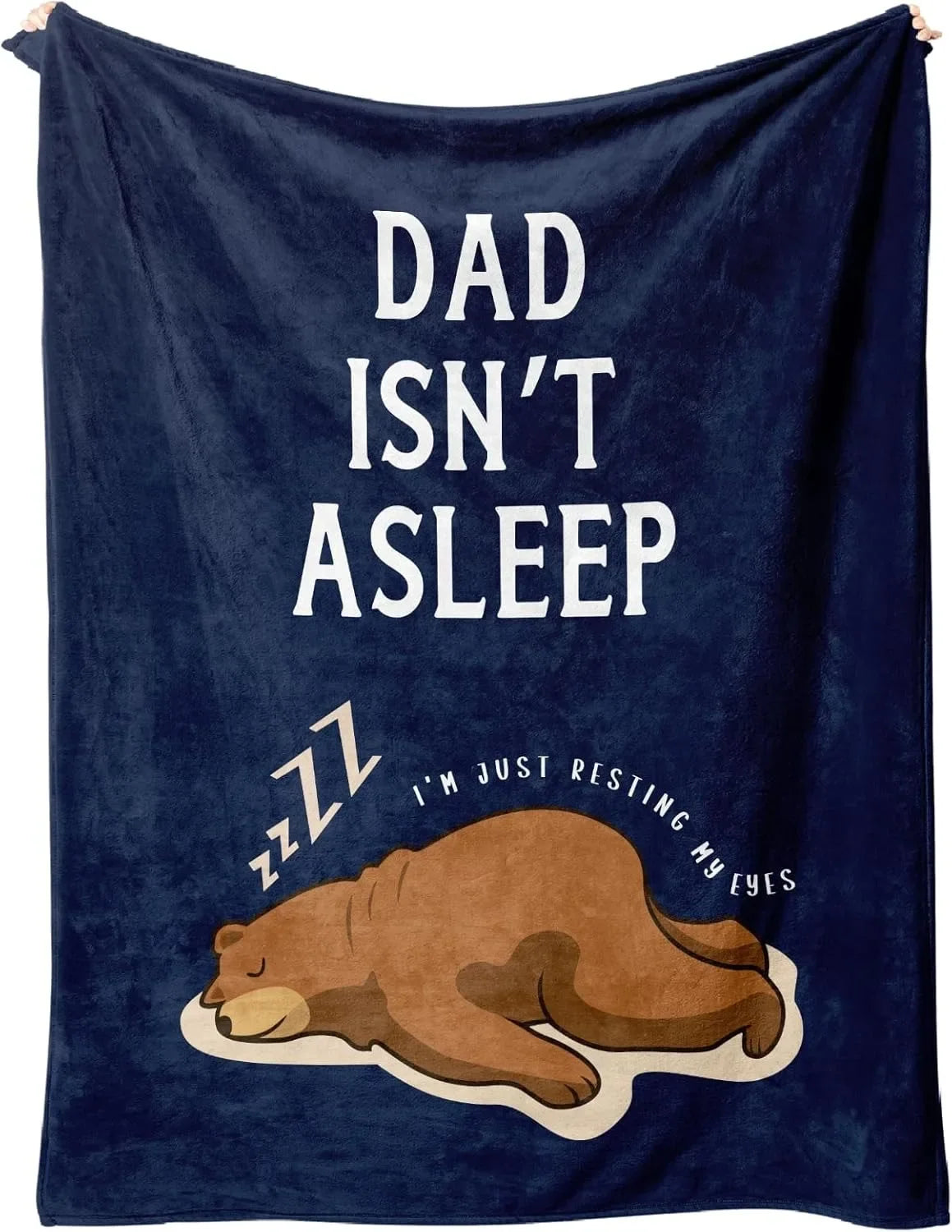 A dark blue knit blanket featuring white text that reads Dad isn't asleep andzzz I'm just resting my eyes above a sleeping be