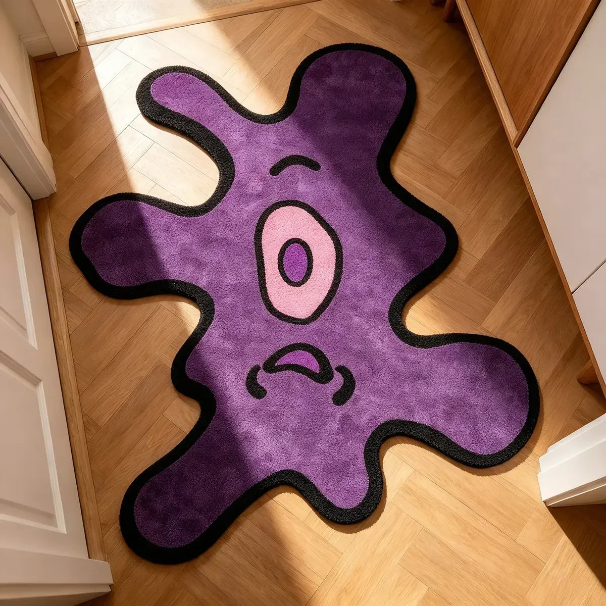 A purple and black playful one-eye monster area rug placed on a light wood floor.