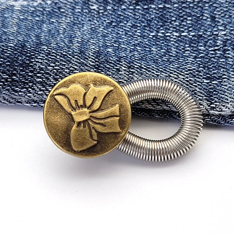 A round brass button with a fabric flower design attached to a silver spring ring.