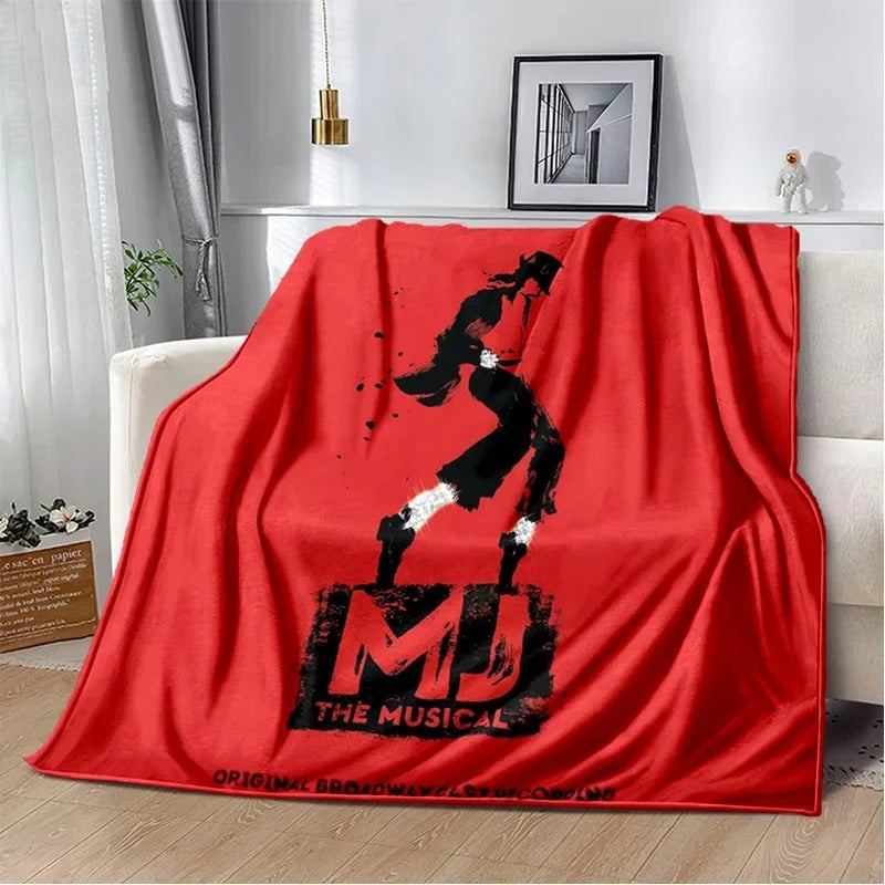 A red flannel throw blanket featuring a black silhouette of a dancer and the text THE MUSICAL