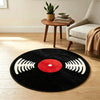 A round black rug with a red center and white sound wave graphics, placed on a light wooden floor.
