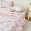 Pink floral quilted bedspread with pink pillow and white bedding