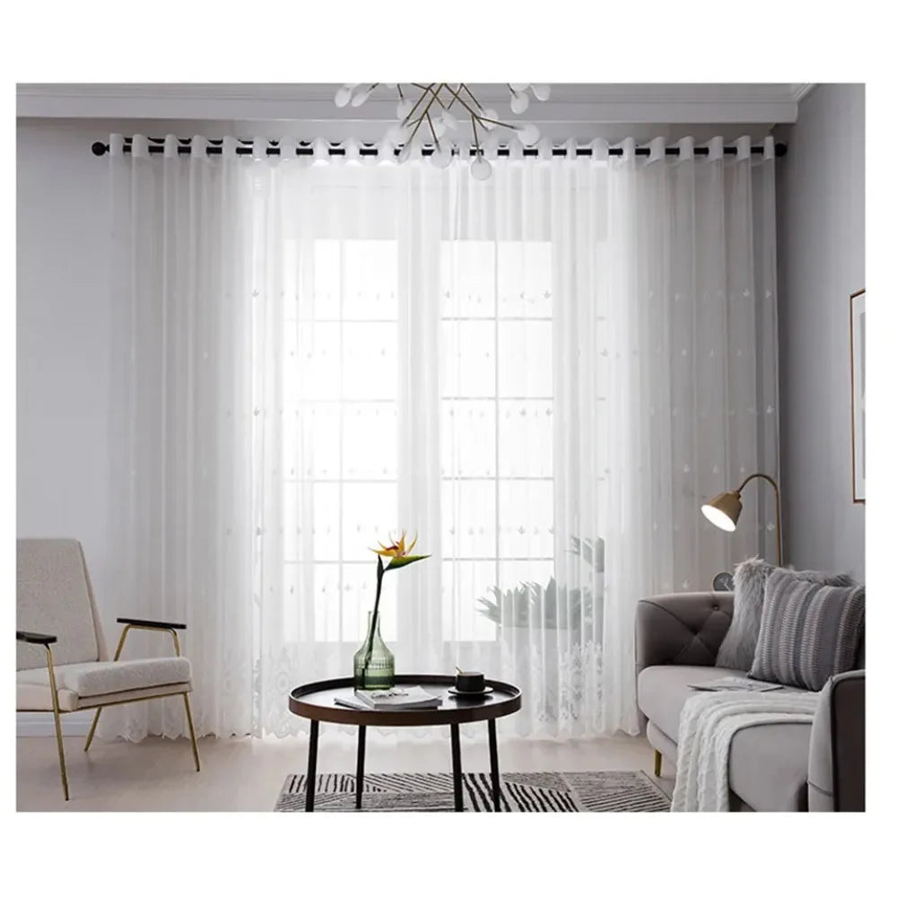 White embroidered floral tulle window curtain hanging in a modern room