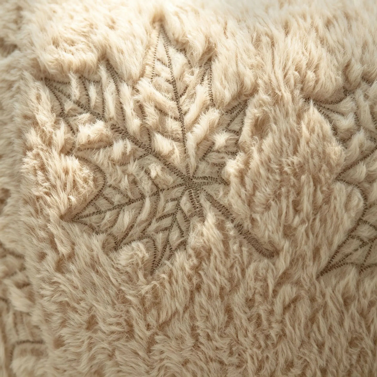 Close-up of fuzzy beige throw pillow covers featuring a detailed maple leaf embroidery pattern.