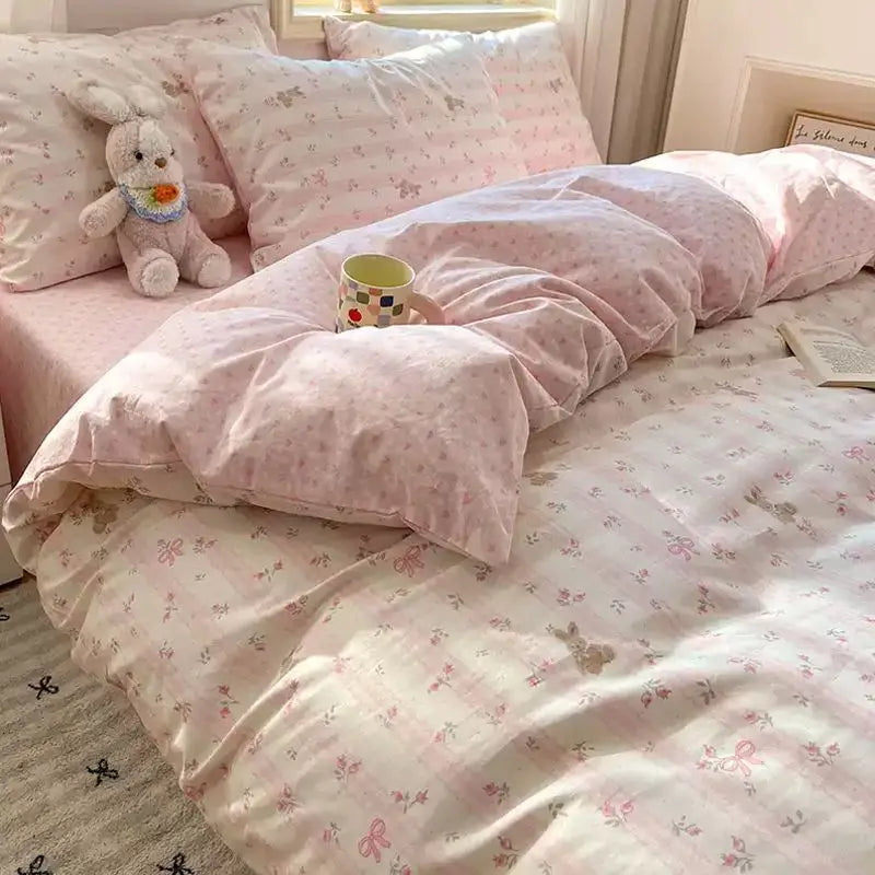 A pink floral bedding set featuring a duvet and pillows with a white unicorn plush toy.