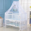 A white foldable mosquito net canopy is set up over an infant cot for protection.