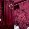 Deep magenta draping stretch fabric used as a luxurious curtain or backdrop.